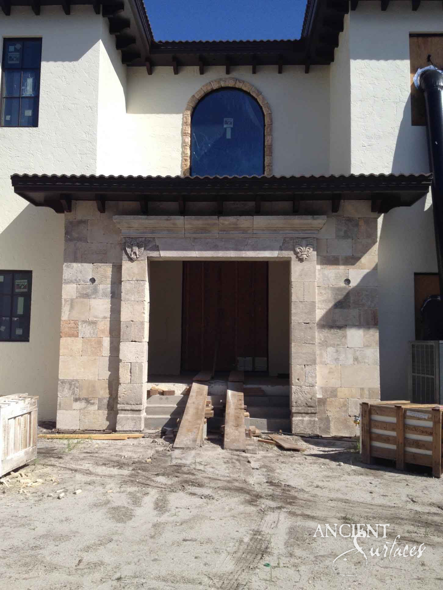 Limestone entry surround of ashlar blocks with carved fleur-de-lis corbels at the lintel